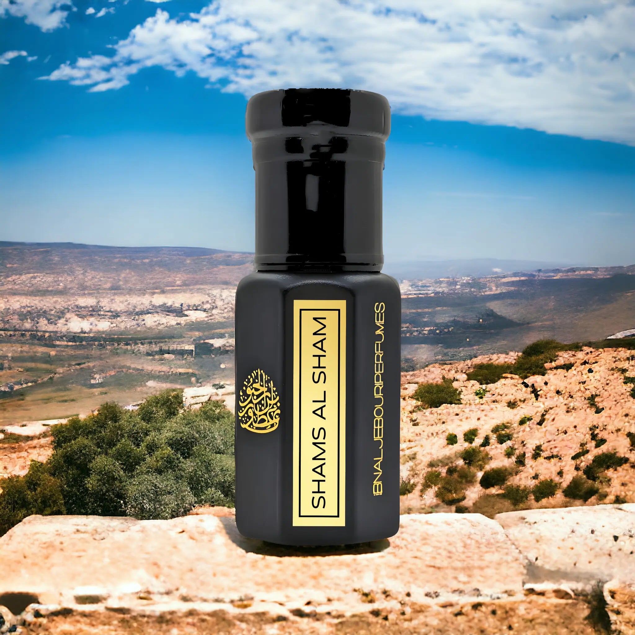 Black glass perfume bottle labeled Shams Al Sham with gold accents, set against a scenic Lebanese landscape.